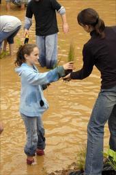 Teacher handing student wetland plants to put in newly established pond.jpg